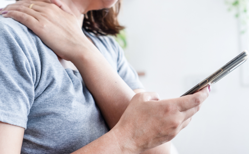 Woman experiencing neck pain from looking down on phone